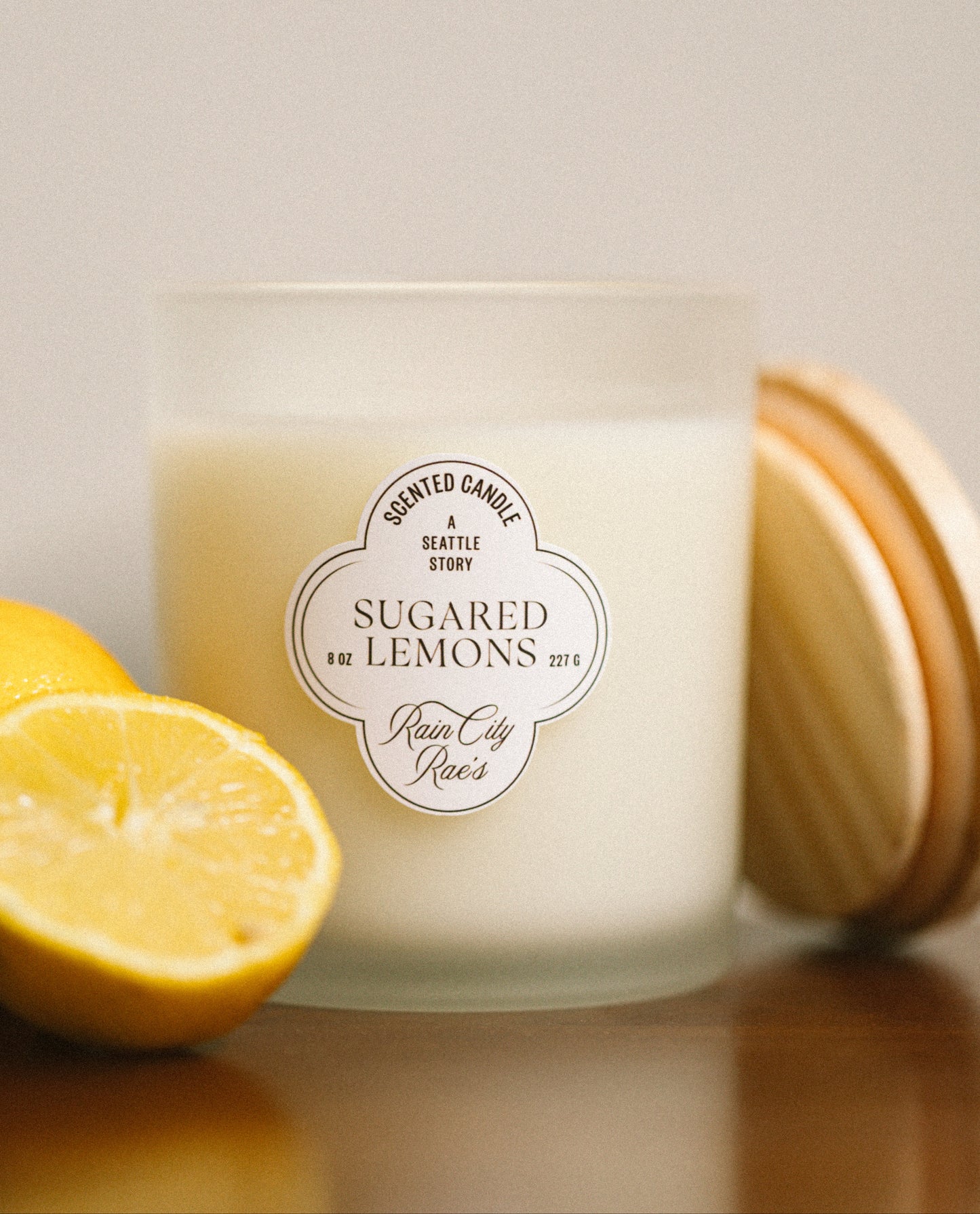 Candle labeled 'Sugared Lemons' with a lemon next to it on a reflective wooden table