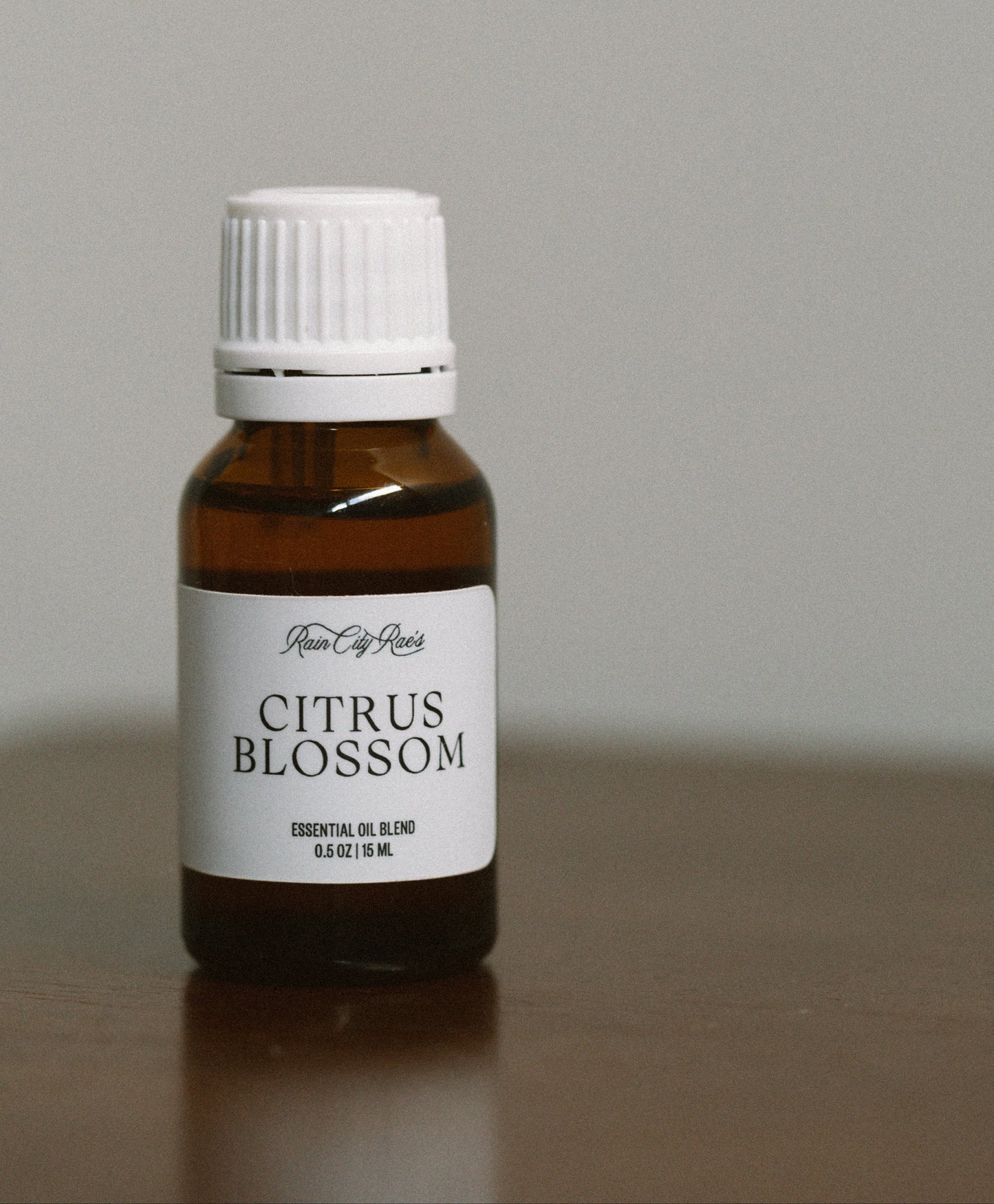 Amber bottle of Citrus Blossom essential oil with a white cap on a gray background