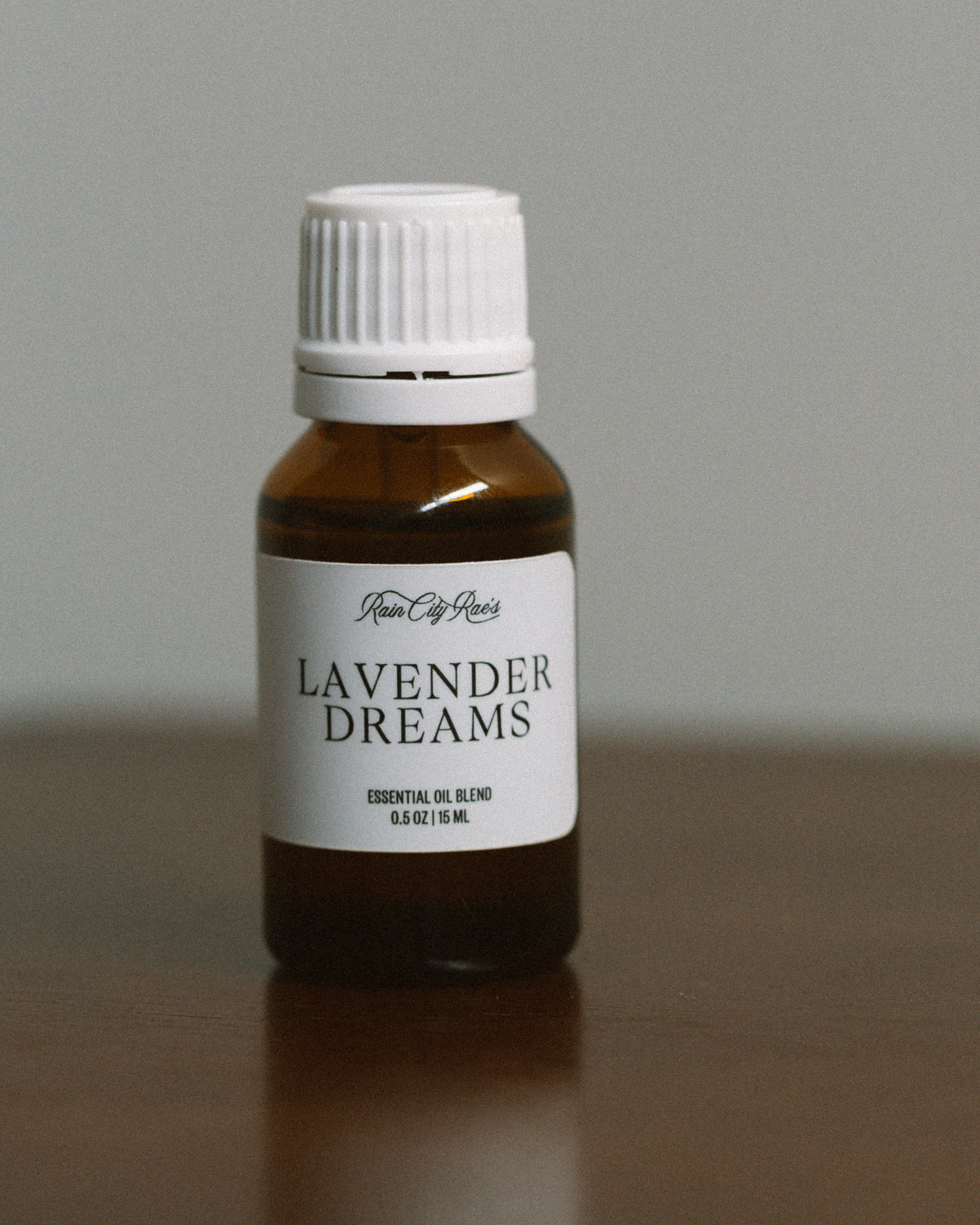 Bottle of 'Lavender Dreams' essential oil on a reflective surface with a neutral background
