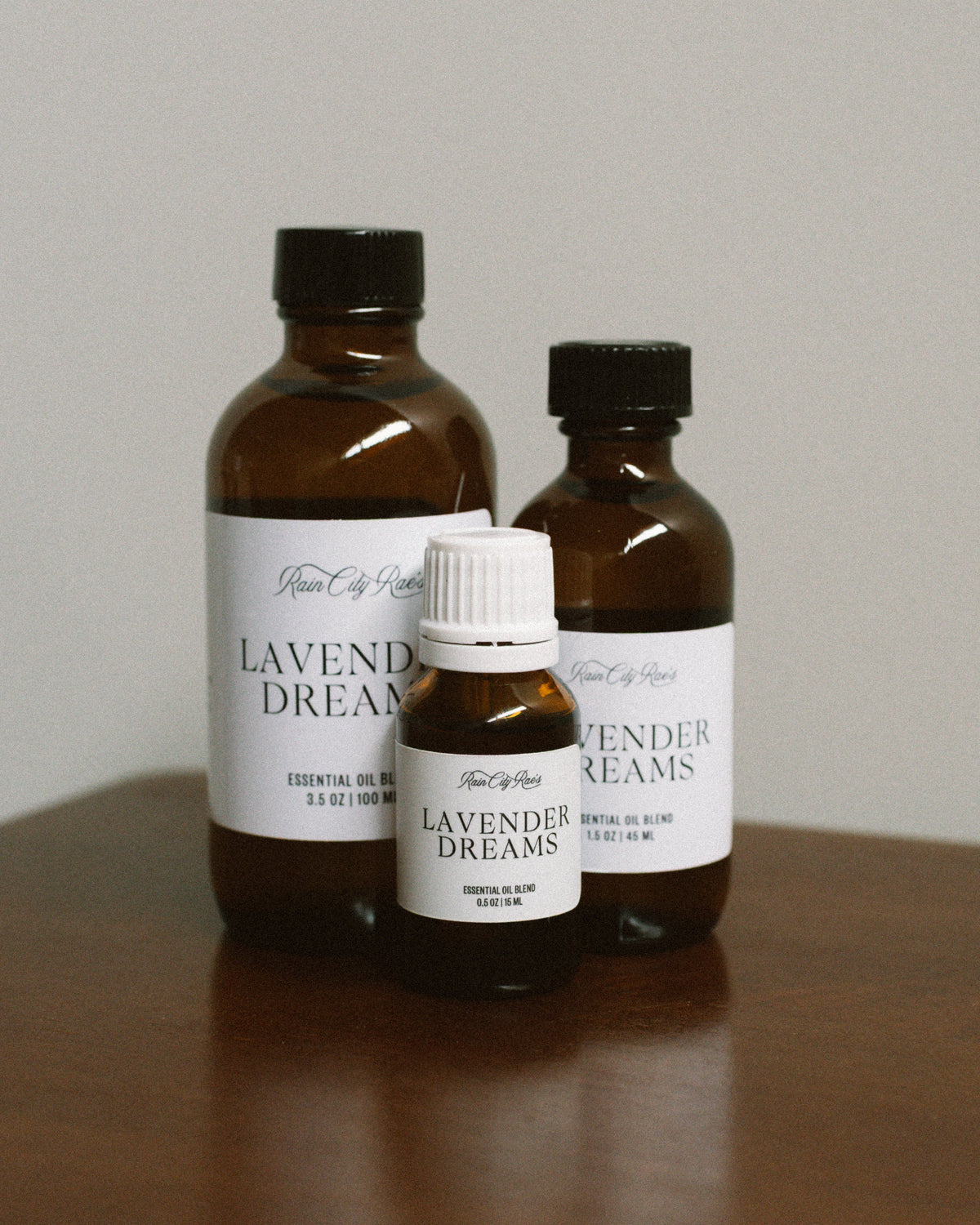 Three bottles of Lavender Dreams essential oil on a wooden surface with a plain background