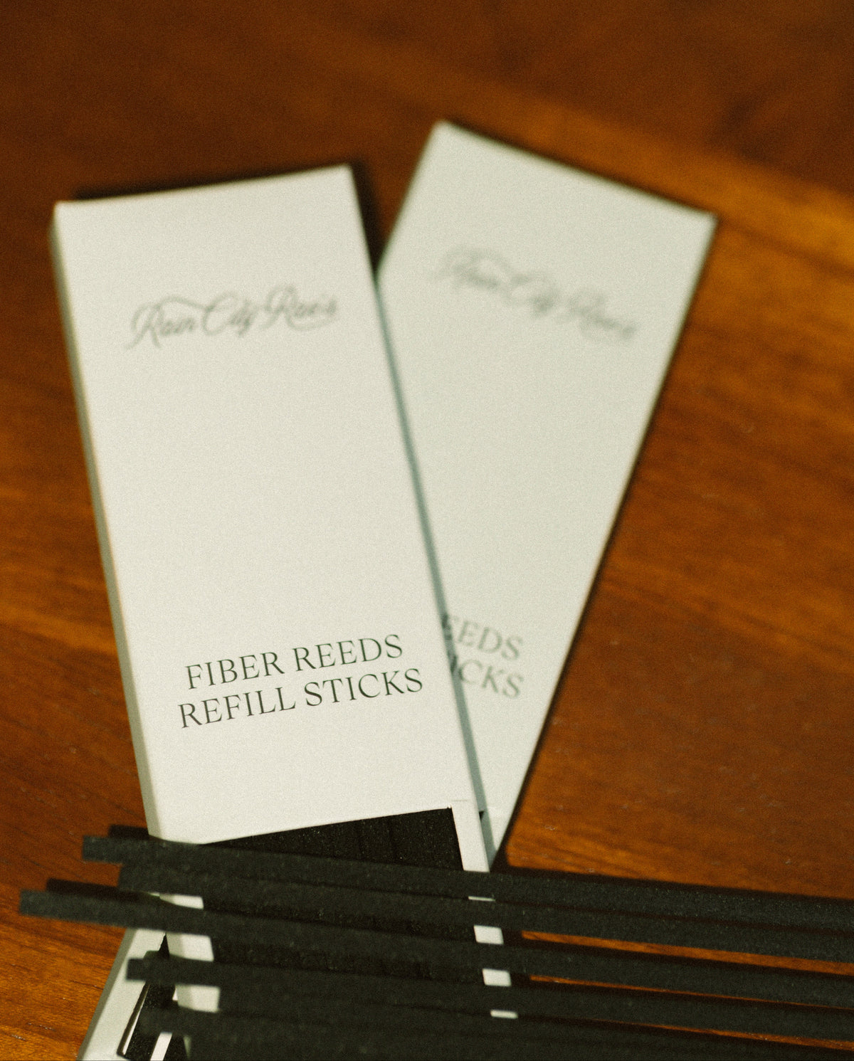 Two black fiber reeds refill stick packs on a wooden surface By Rain City Rae's