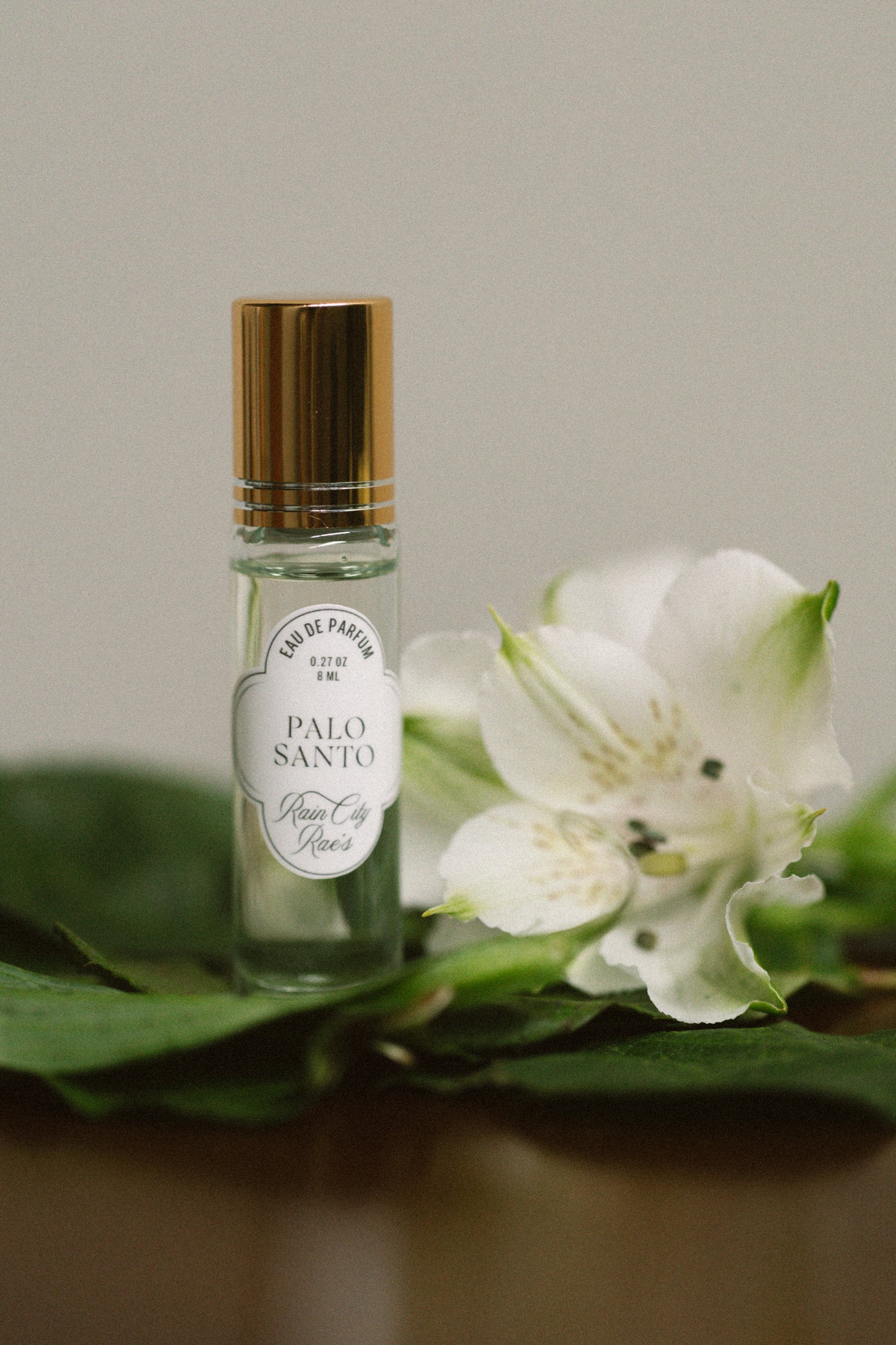 Roll-on bottle labeled 'Palo Santo' with a white flower and green leaves on a neutral background