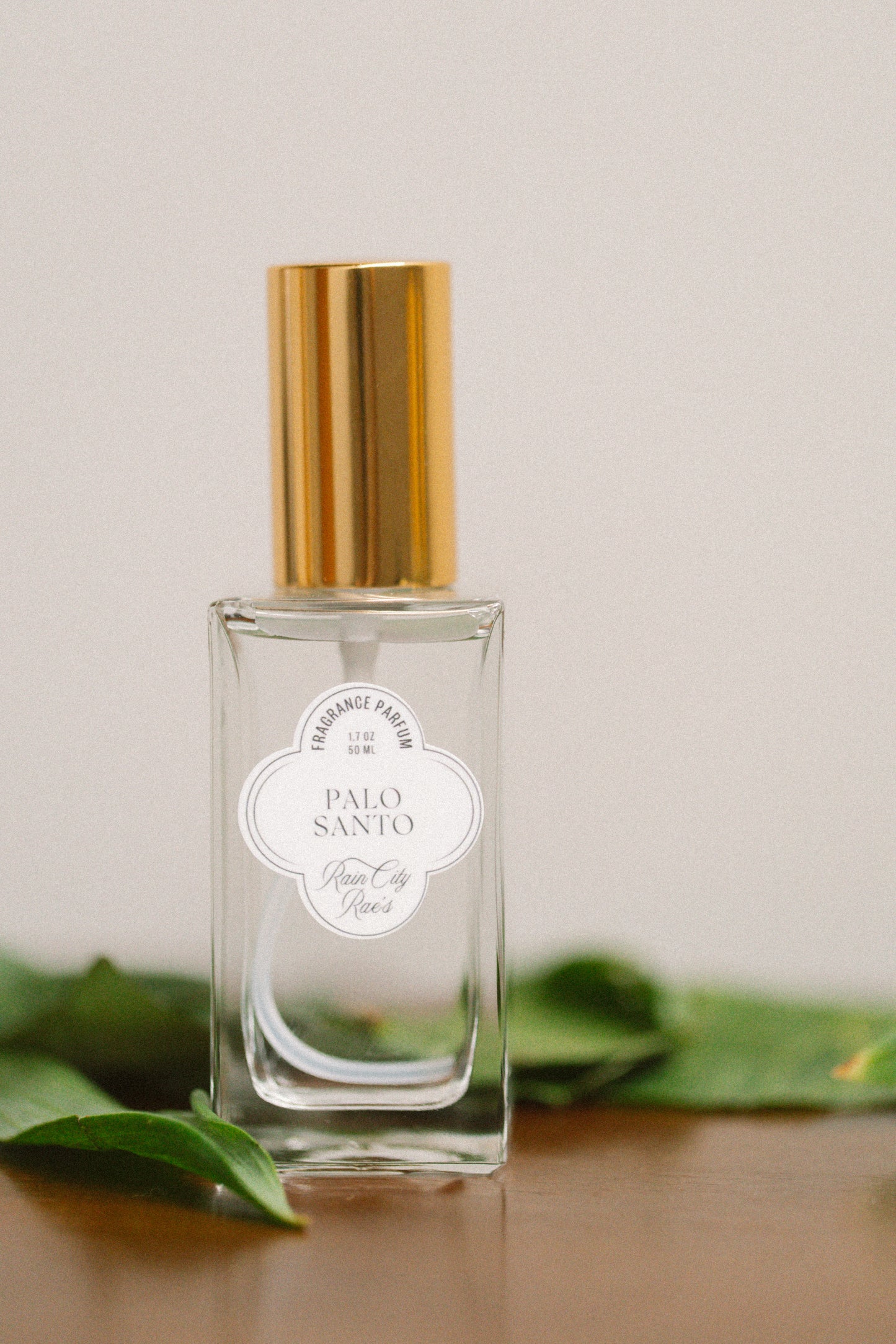 Perfume bottle labeled 'Palo Santo' with a gold cap on a neutral background